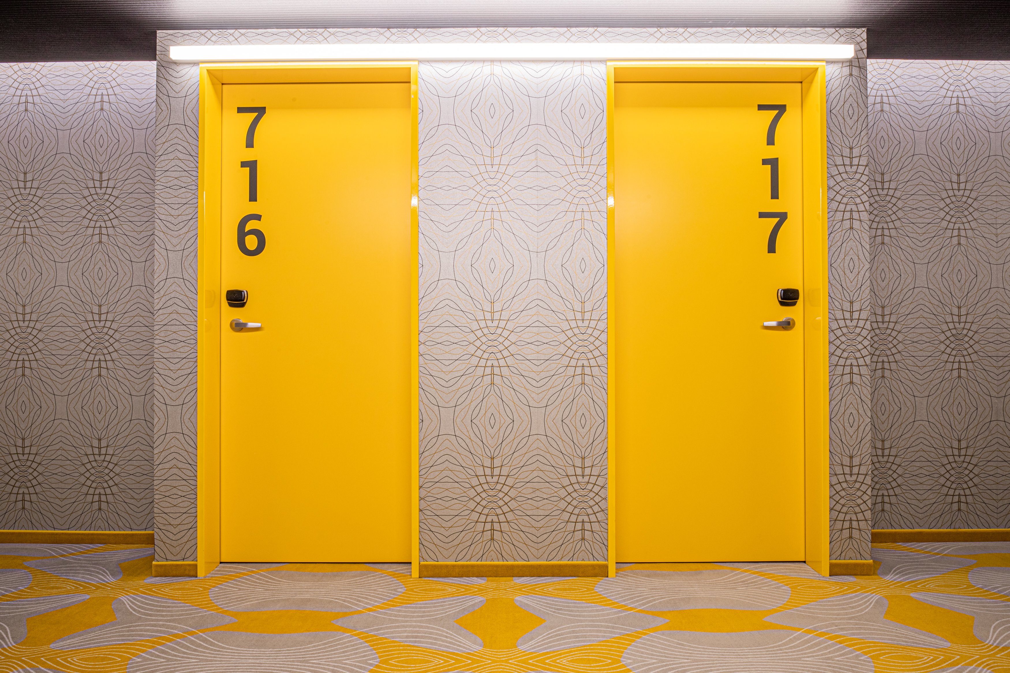 Zwei gelbe Hotelzimmertüren mit groß aufgedruckten Zimmernummern