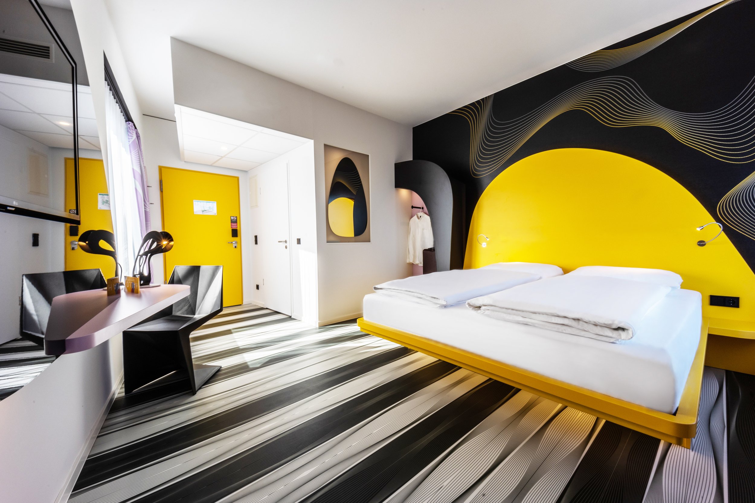 Ein Zimmer mit gelbem Bett und schwarz-weißen Boden im prizeotel Bonn