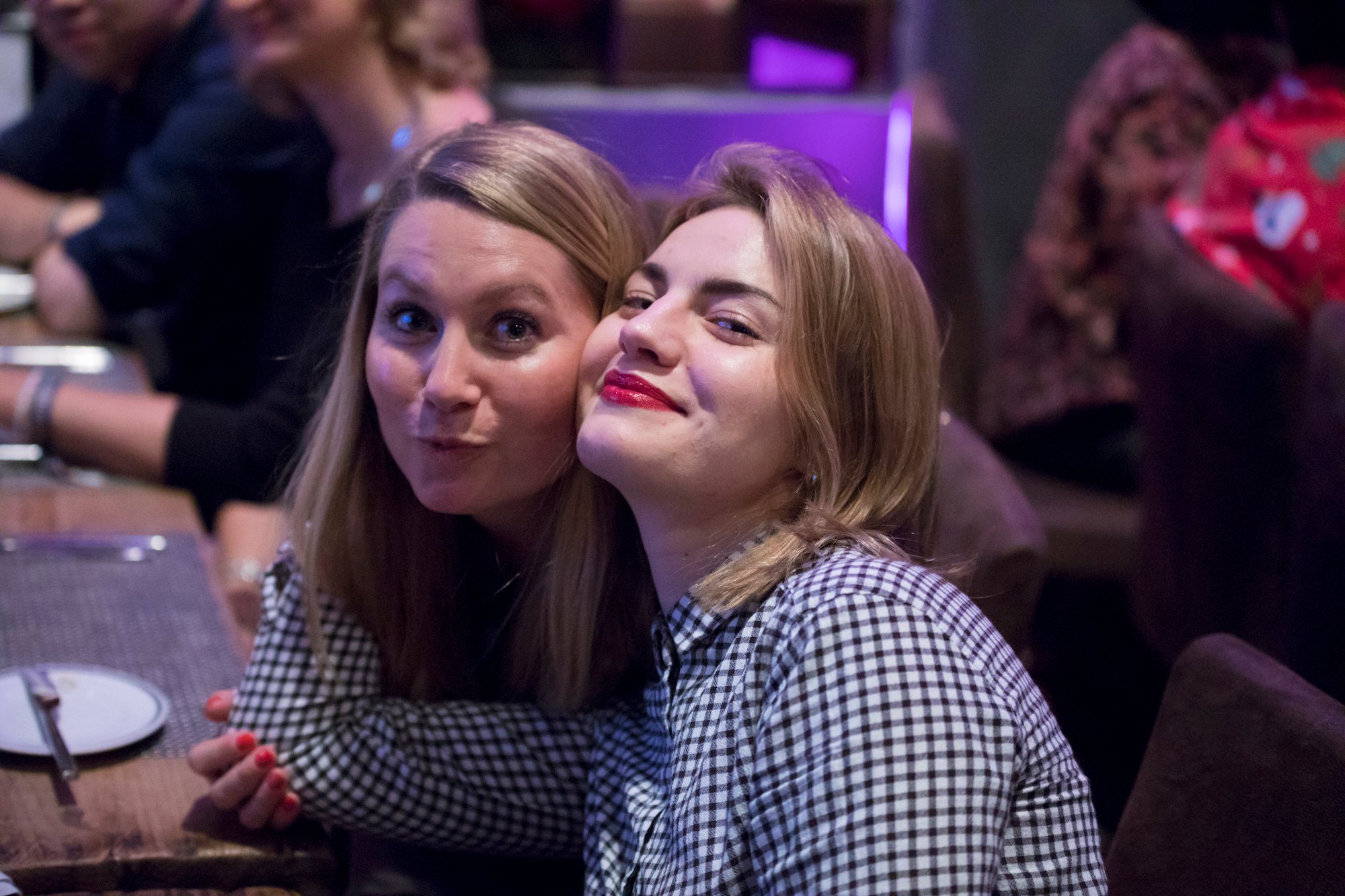 Zwei junge Frauen posieren gemeinsam vor der Kamera an einem Esstisch