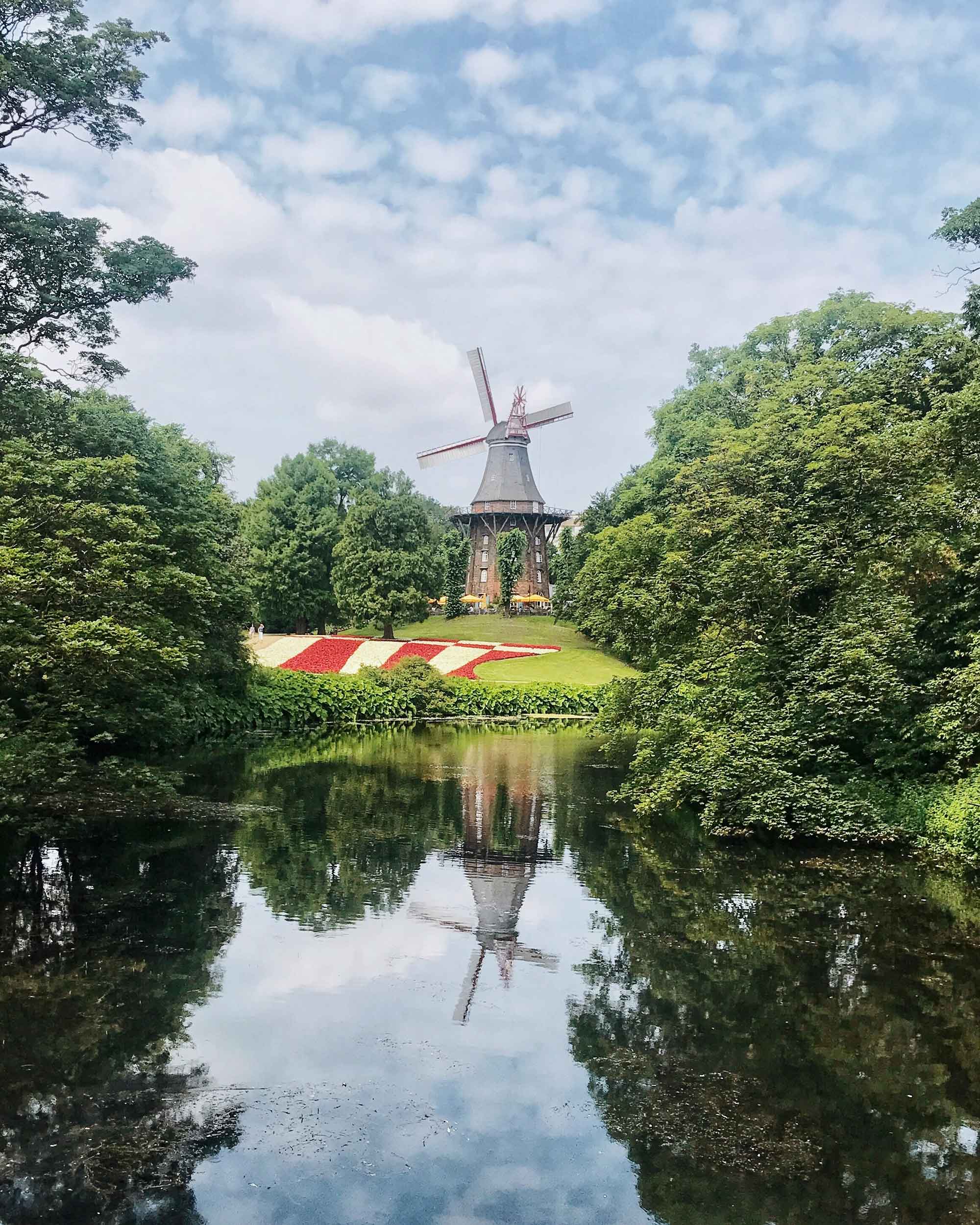 A pond in a park with a mill in the background