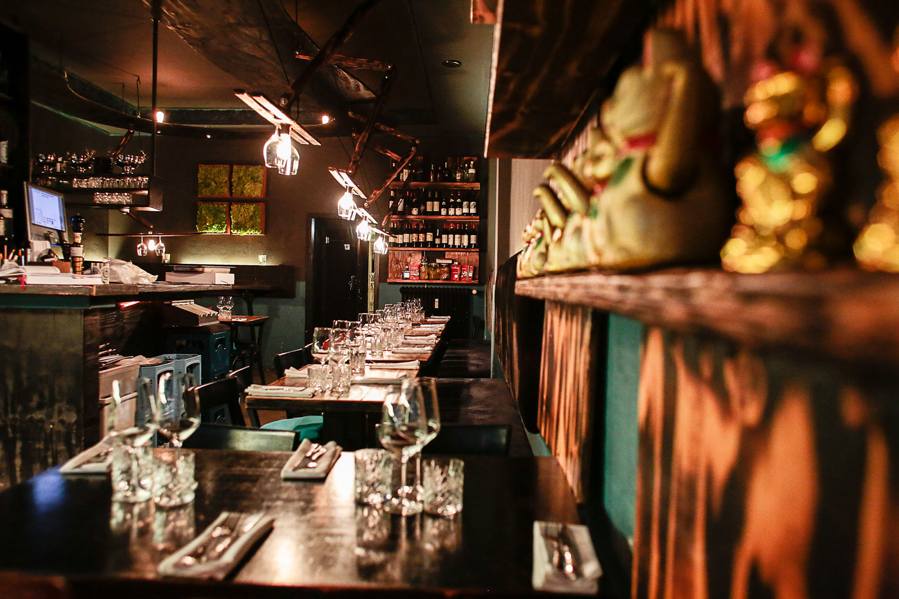 Dunkle Bar mit Tresen und Tischen aus dunklem Holz und aufgestellten Gläsern