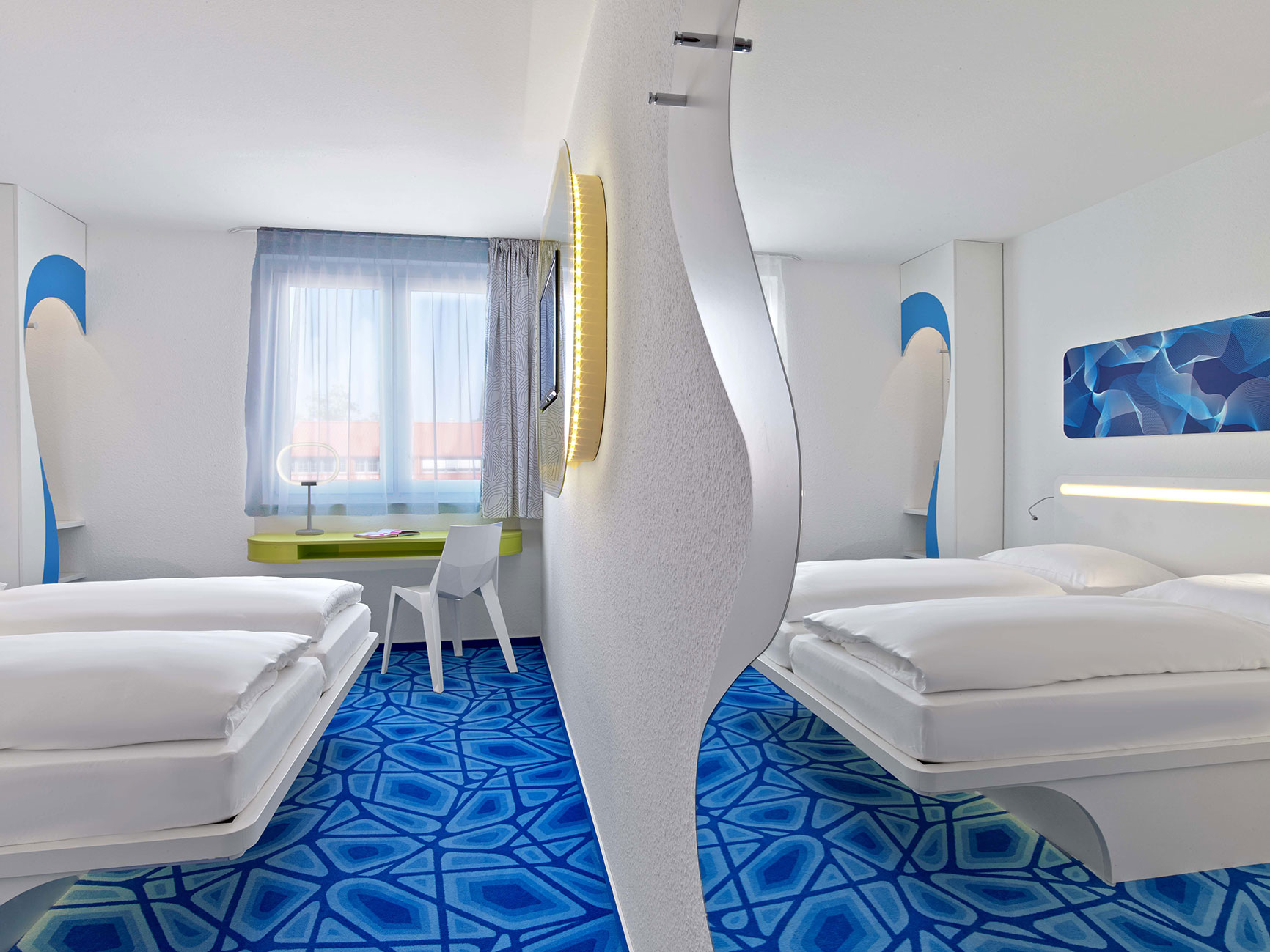 Spiegelung eines Hotelzimmers mit Doppelbett, blauem Fußboden und kleiner Schreibtischecke