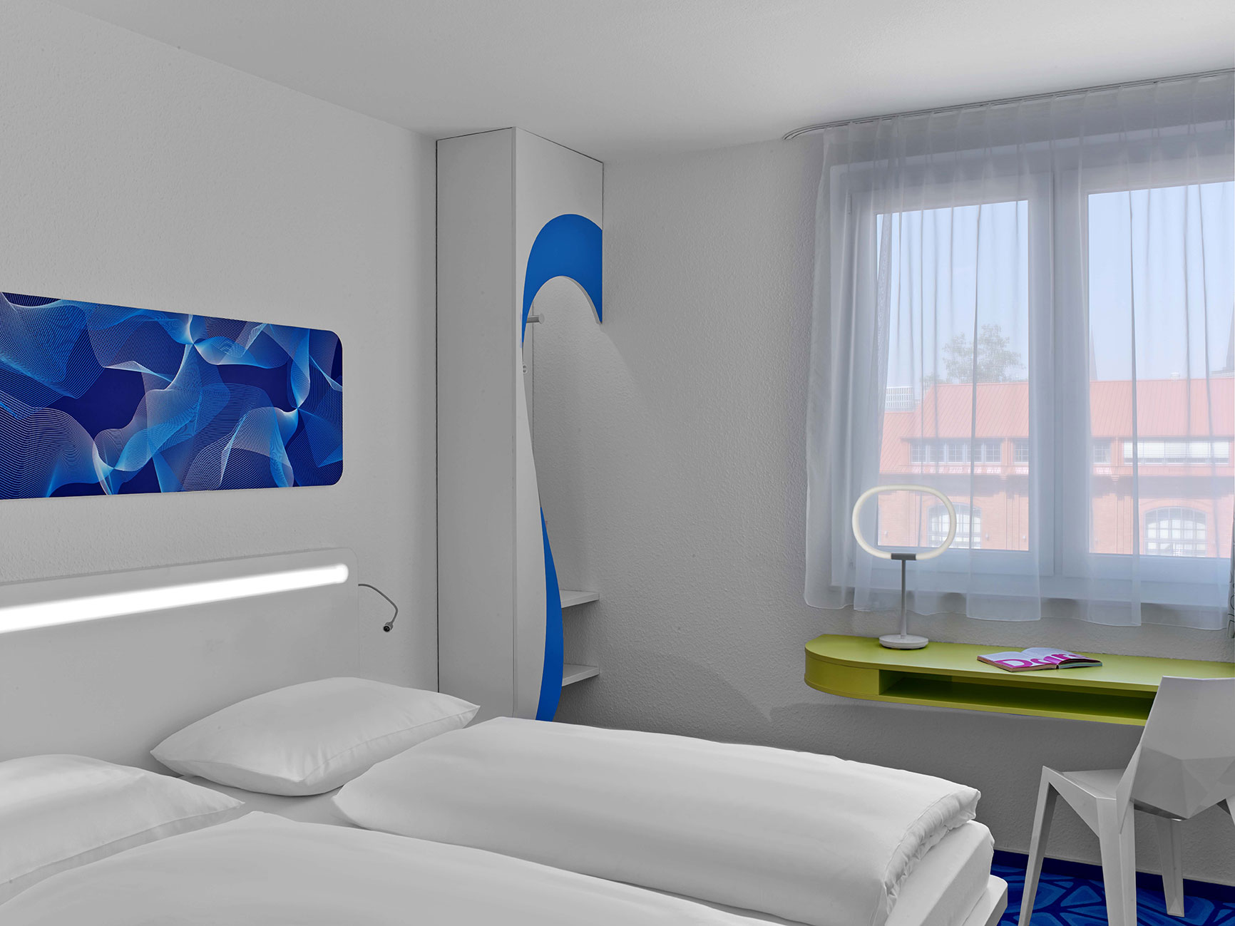 Design hotel room with blue patterns on the floor and wall, as well as a small desk