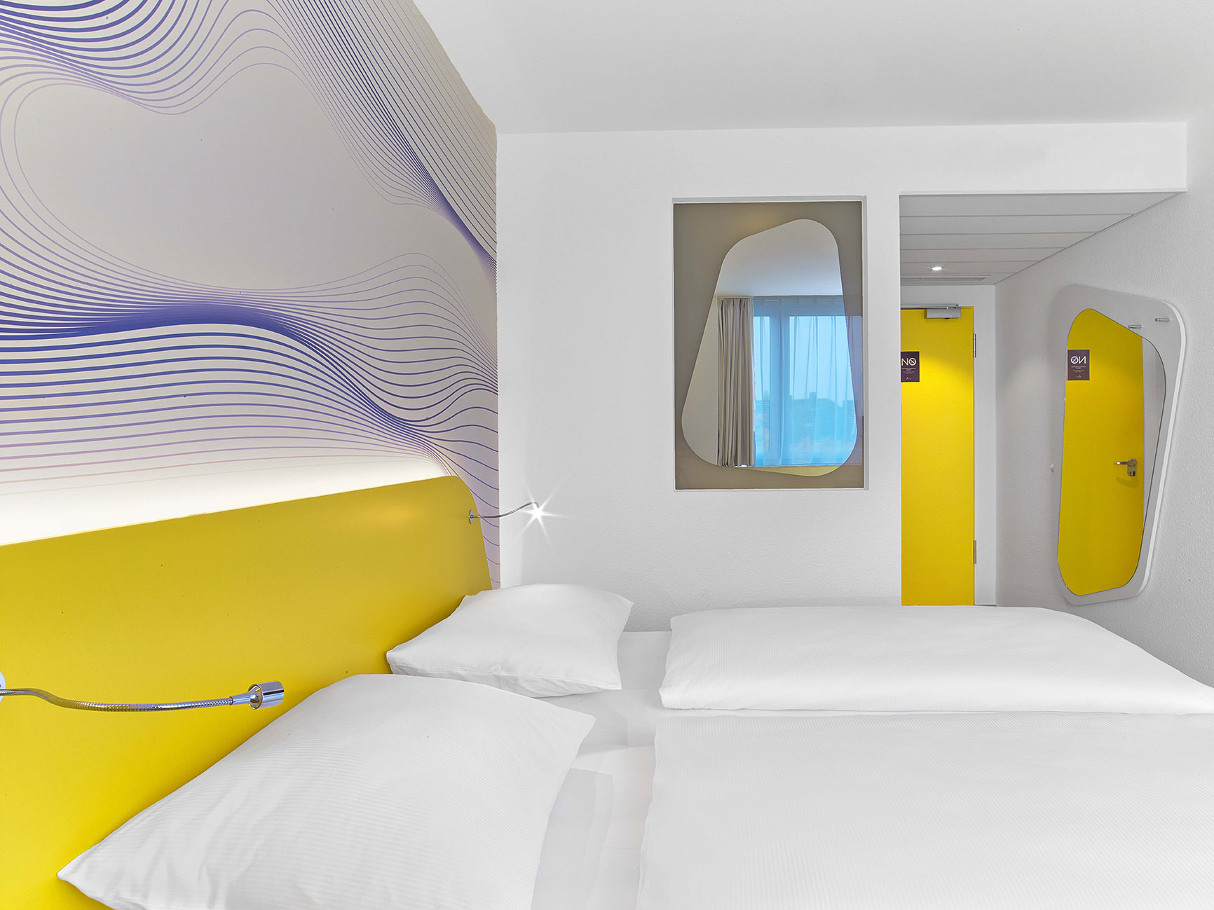 Design room in Hanover with yellow and purple colours, a double bed and a curved mirror