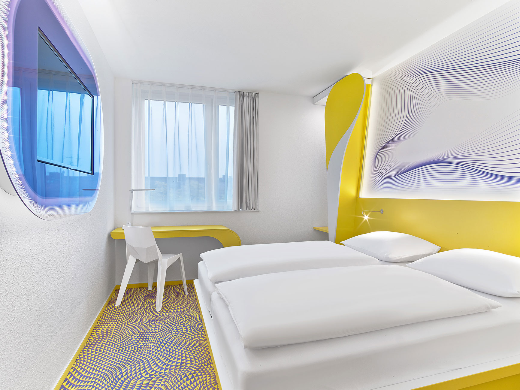 Doppelbett im Designzimmer des Hannover Hotels mit kleiner Schreibtischecke