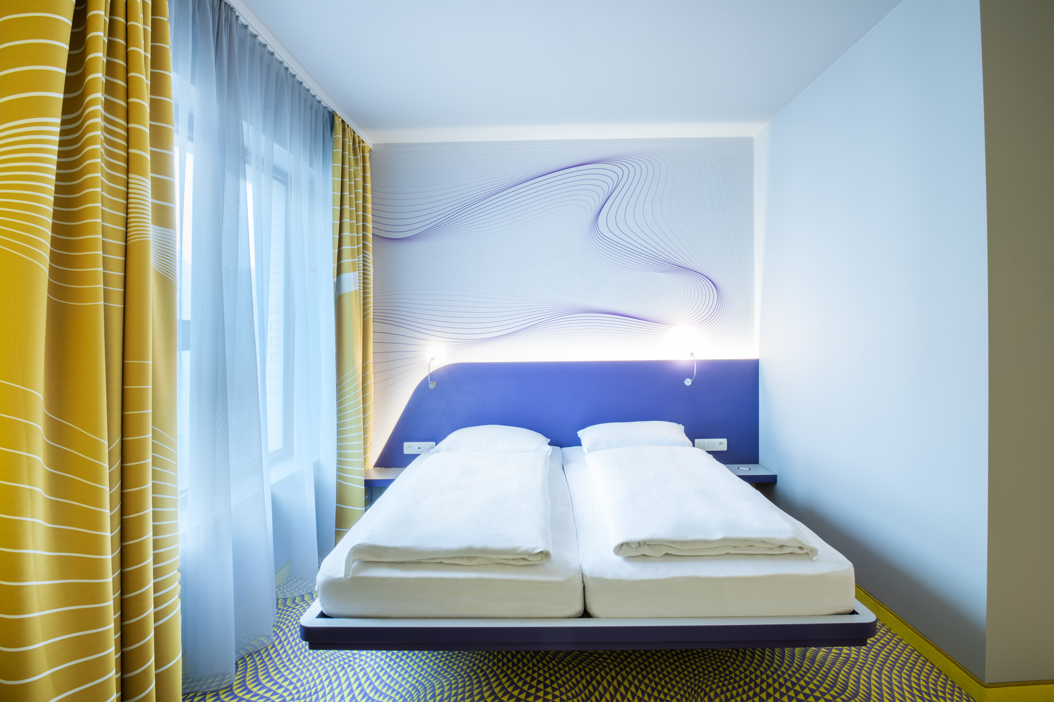 Doppelbett im Design Zimmer nit blau-gelbem Design