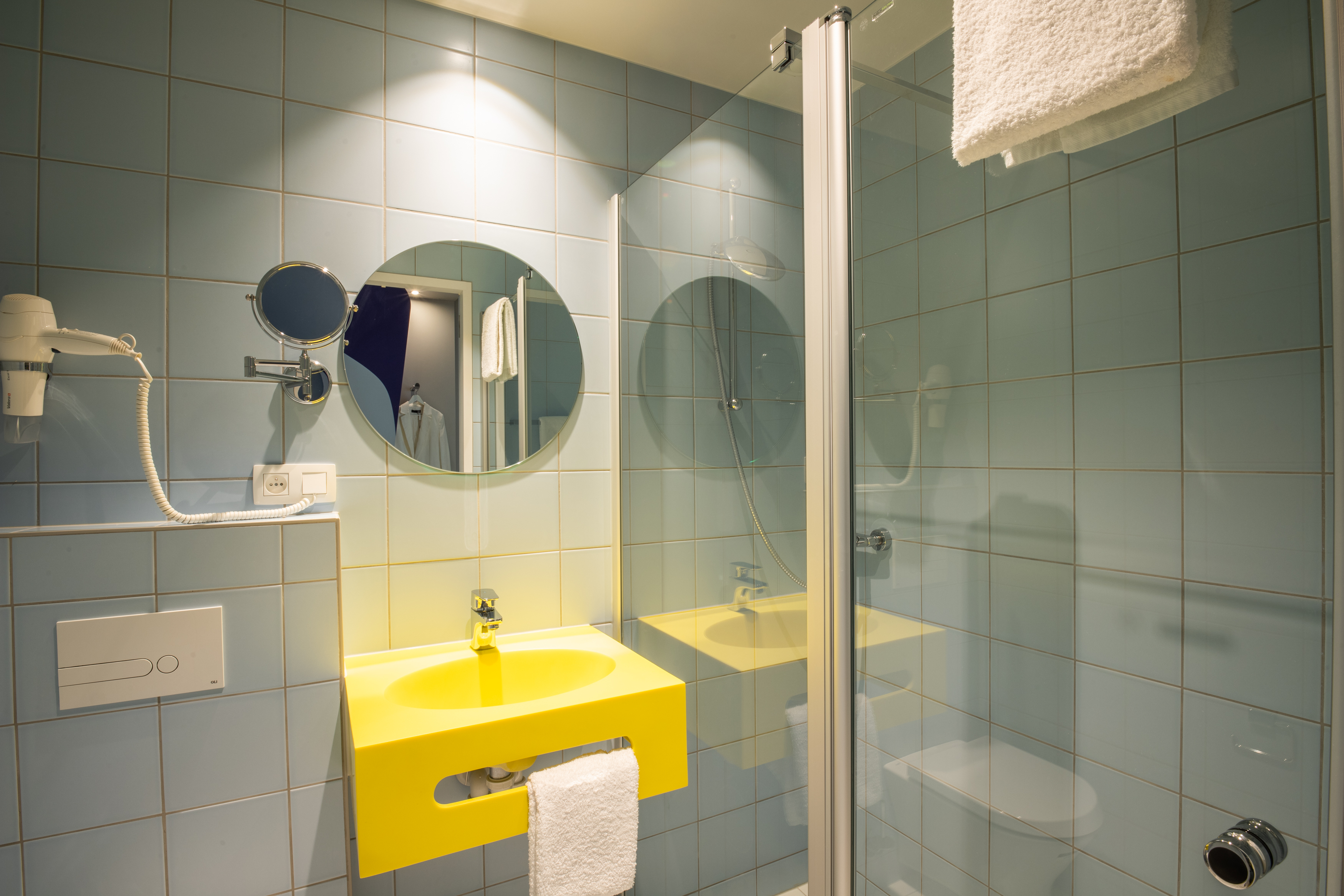 Badezimmer mit gelbem Waschbecken, blauen Fließen und Duschkabine