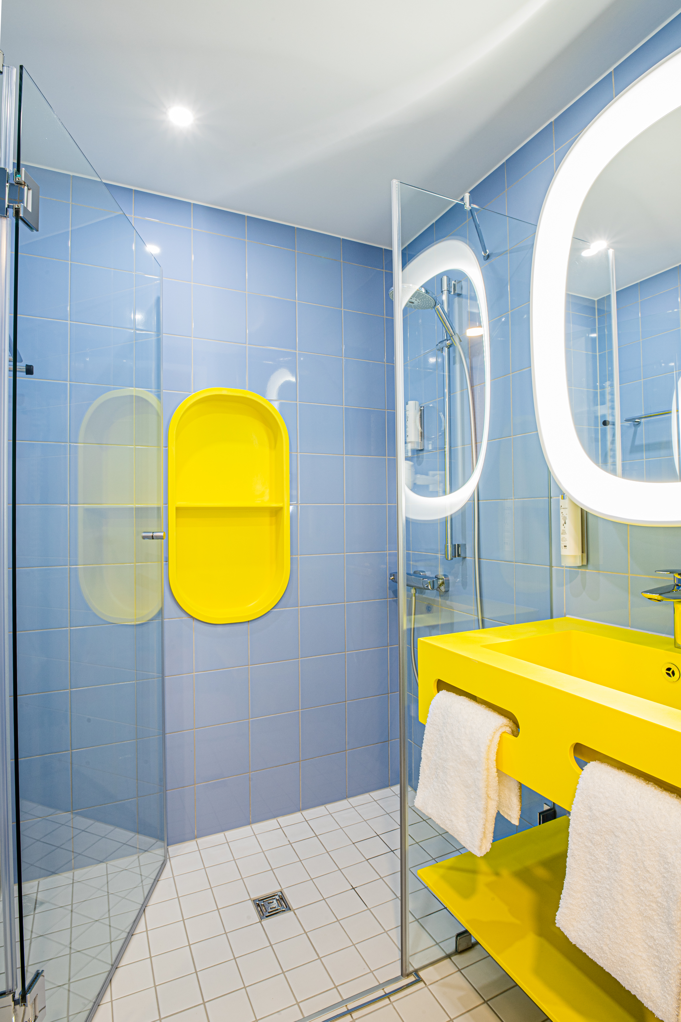Badezimmer mit gelbem Waschbecken, großem Spiegel und begehbarer Dusche