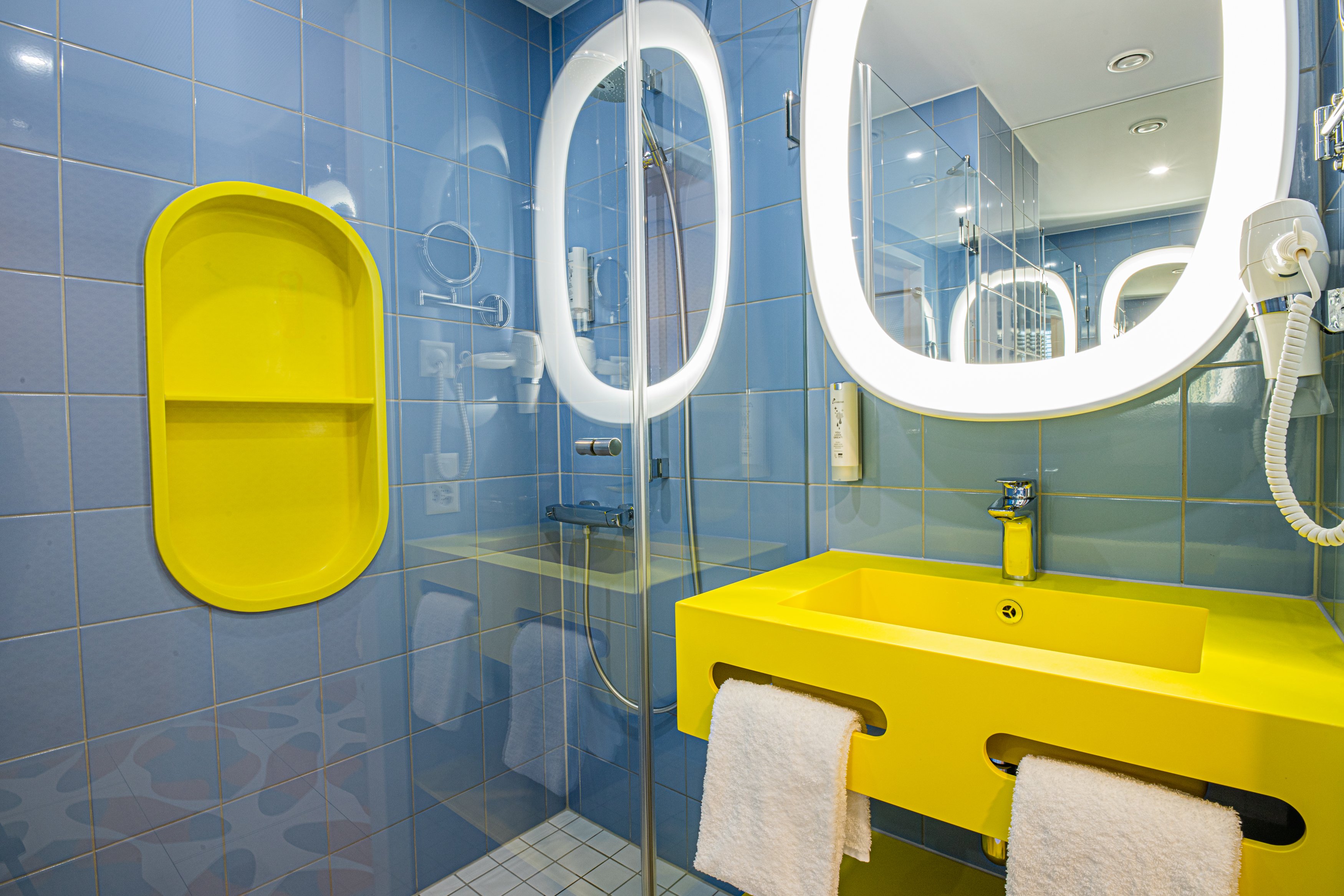 Modernes Badezimmer mit blauen Fliesen und gelben Elementen
