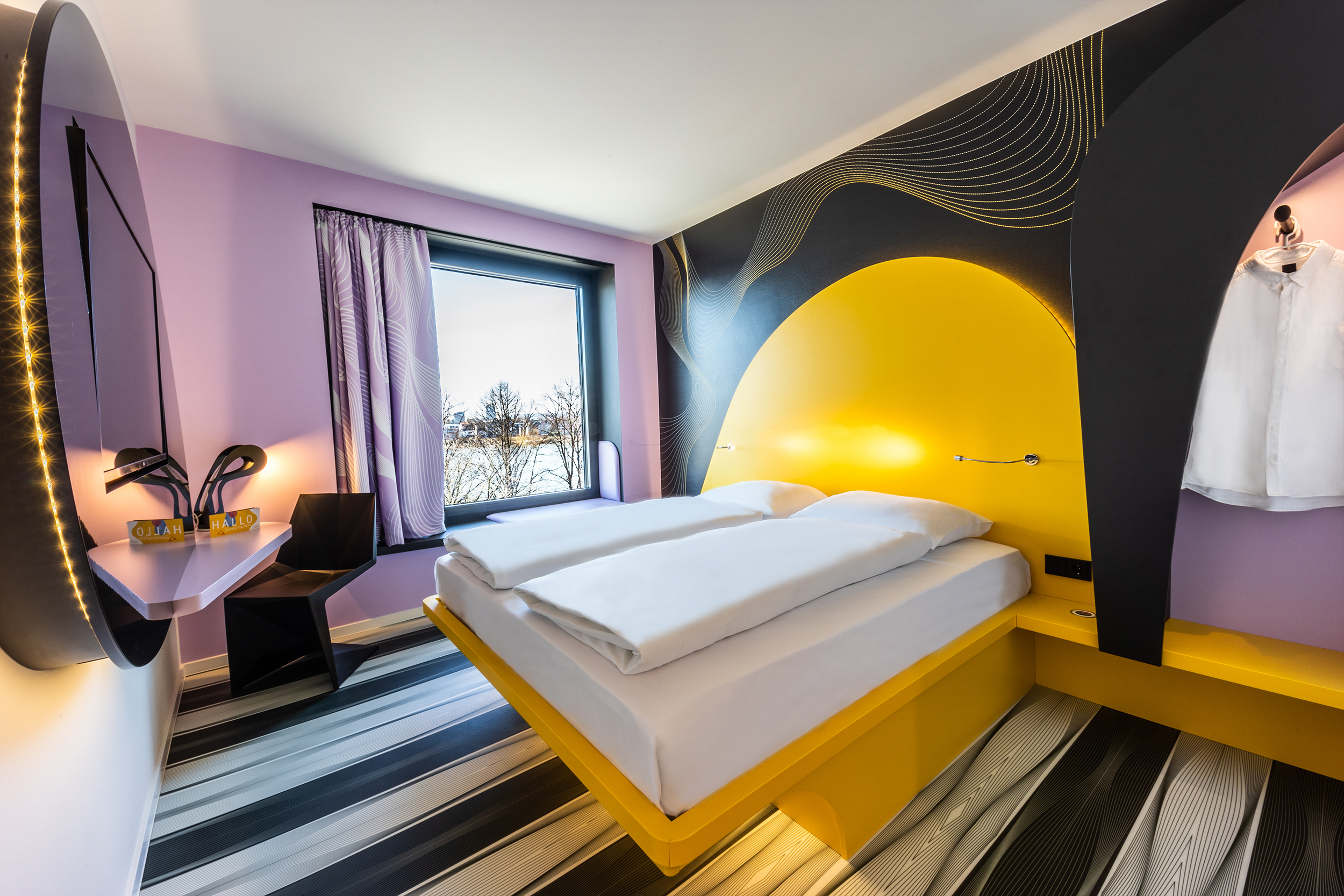 Ein gelb-lila Raum des Hotels mit frisch bezogenem Bett