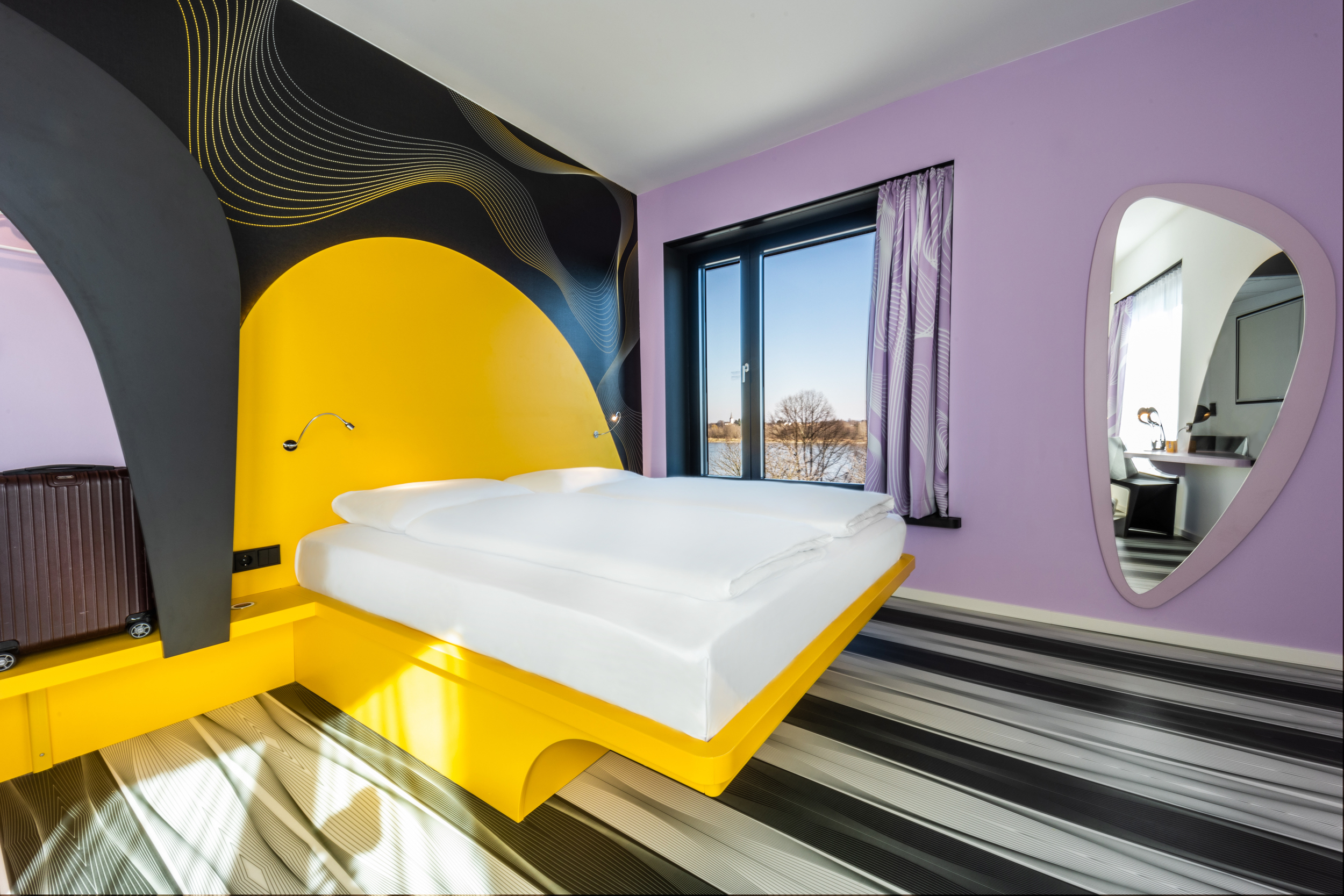 Ein gelbes Bett inmitten eines lila gestrichenen Hotelzimmers
