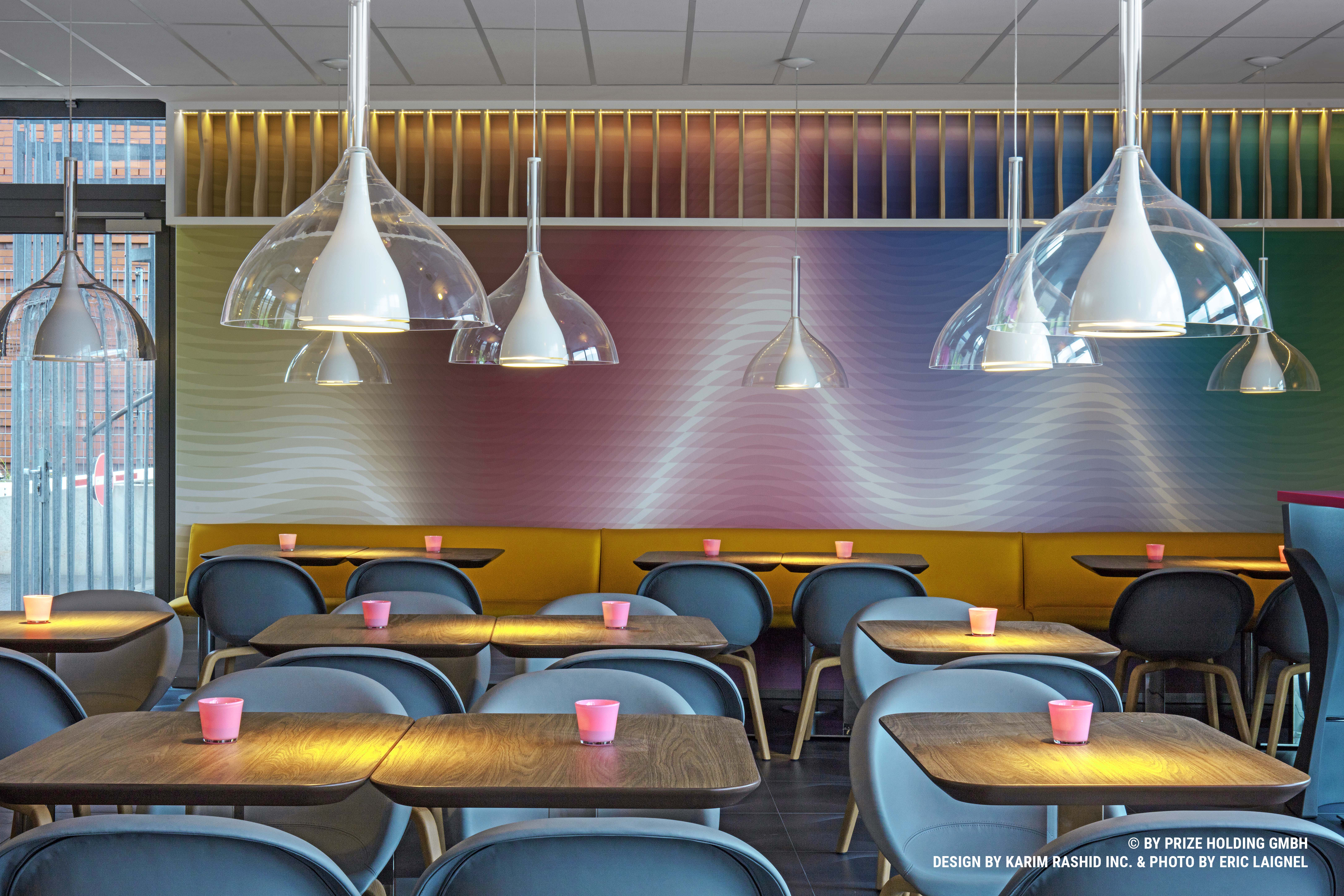 Breakfast lounge in Bremen-City with grey chairs, wooden tables and hanging lamps