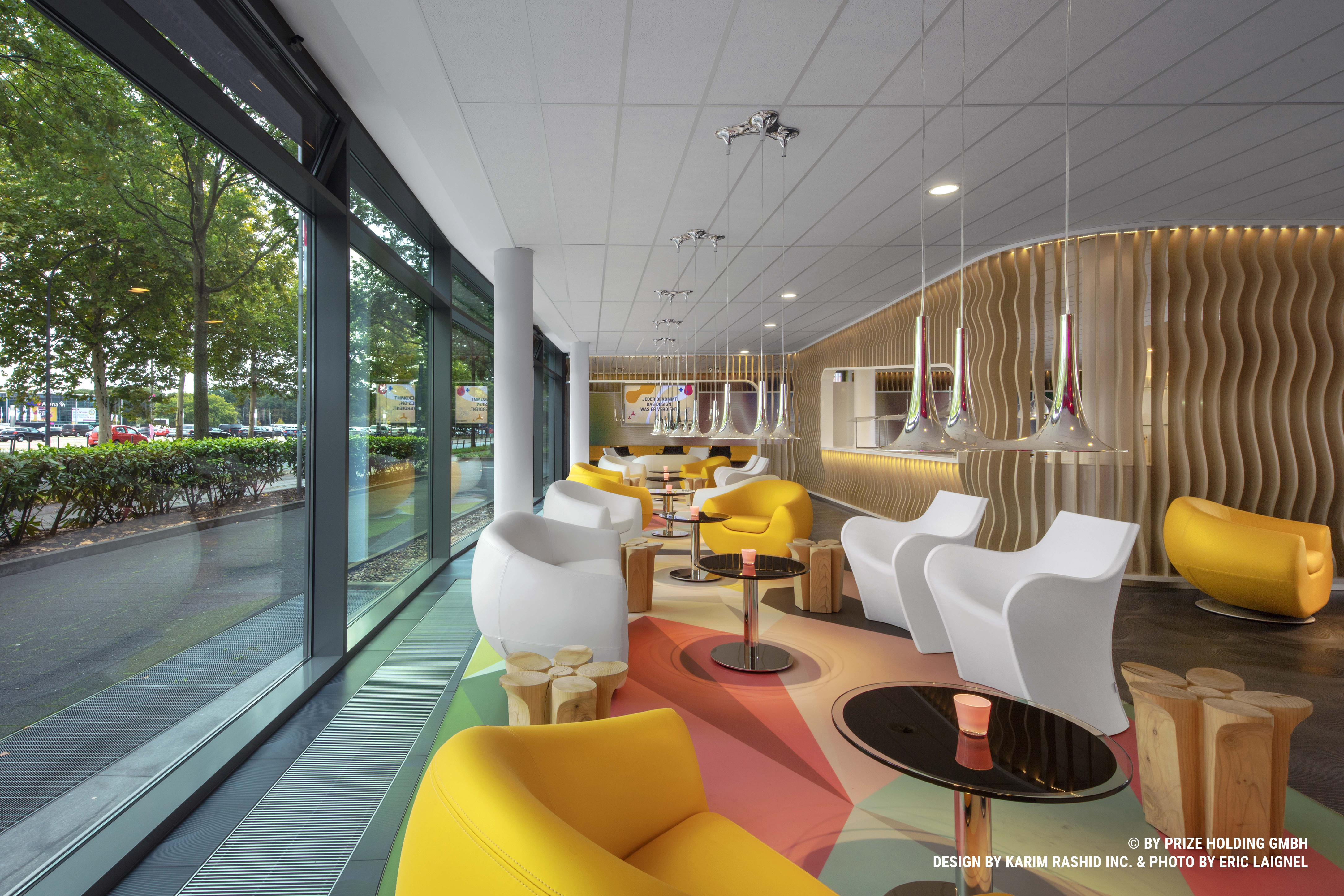 Colourful hotel lobby with single armchairs, round tables and hanging lamps