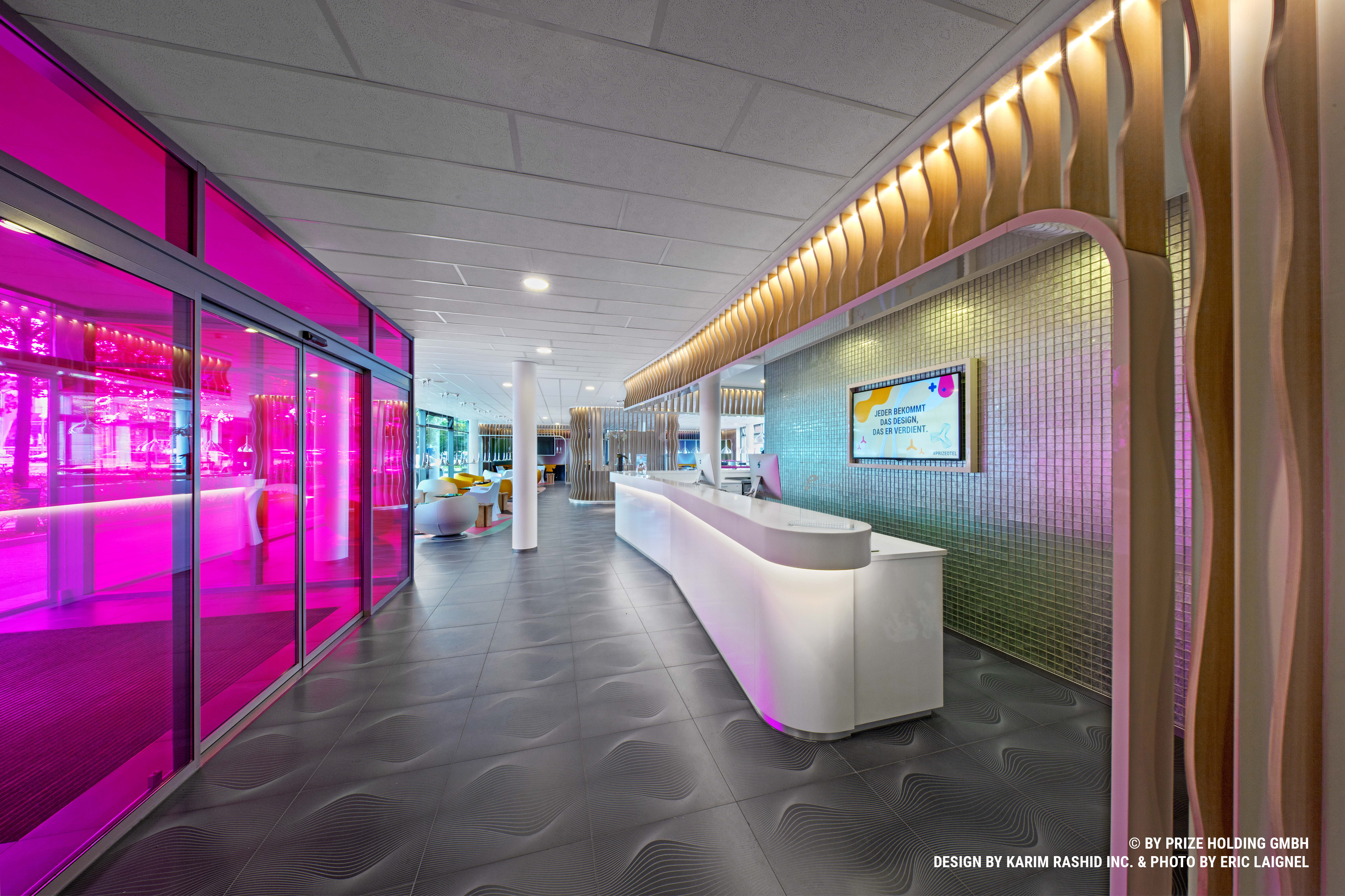 Modern reception in prizeotel Bremen-City with a glass entrance with pink glasses