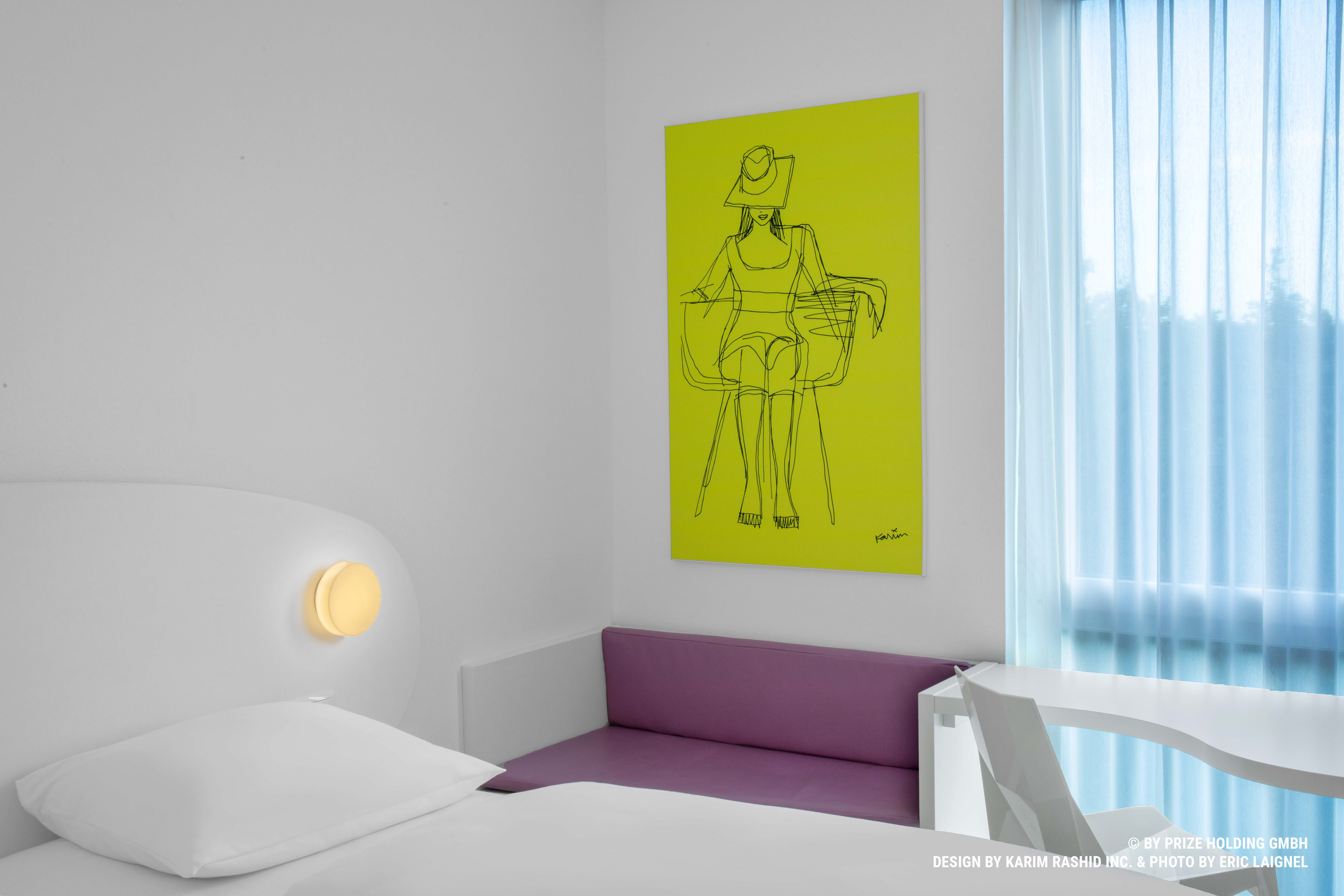 Details eines Hotelzimmers mit einem gelben Bild und einer lila-farbenen Sitzbank 