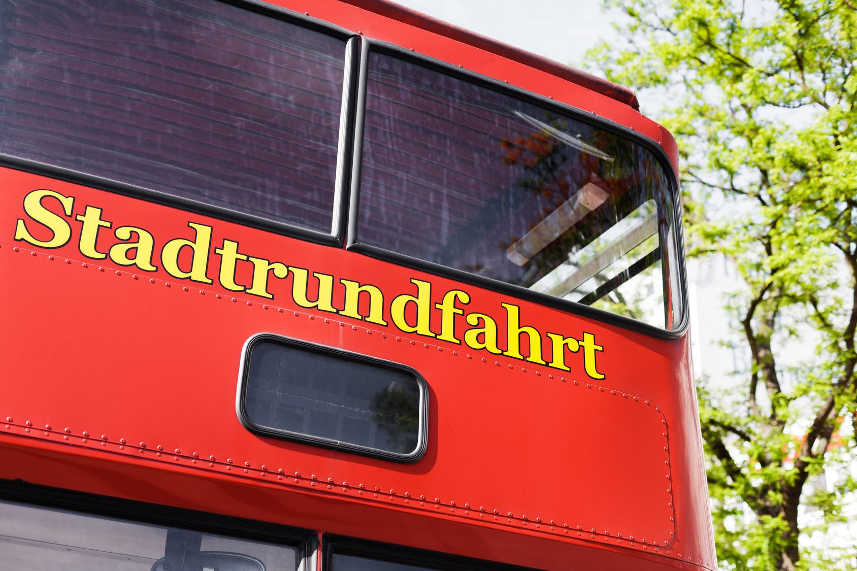 Der hintere Teil eines roten Doppeldeckerbusses mit der Aufschrift Stadtrundfahrt in gelber Schrift