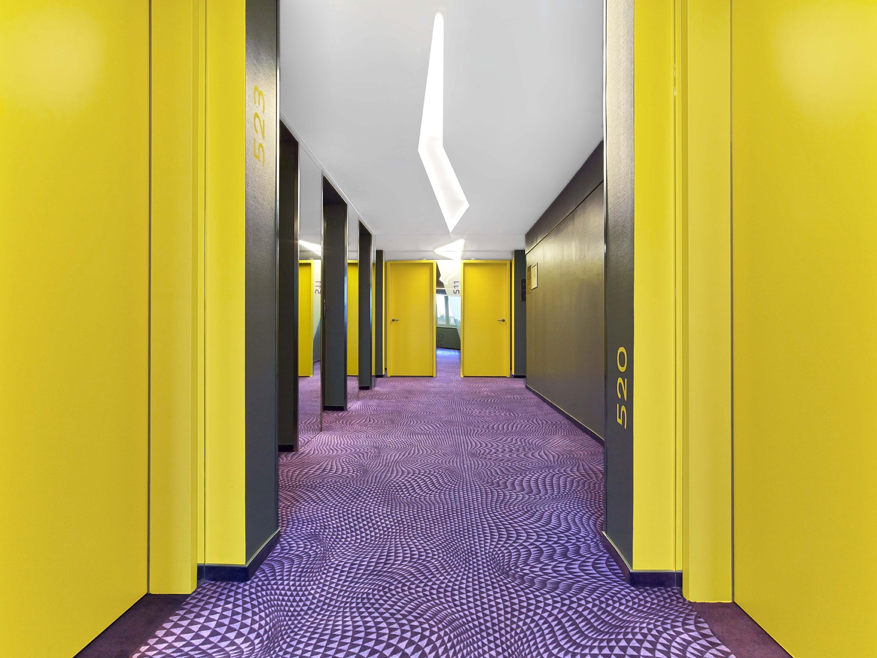 Flur des Designhotels mit violettem Boden und gelben Türen