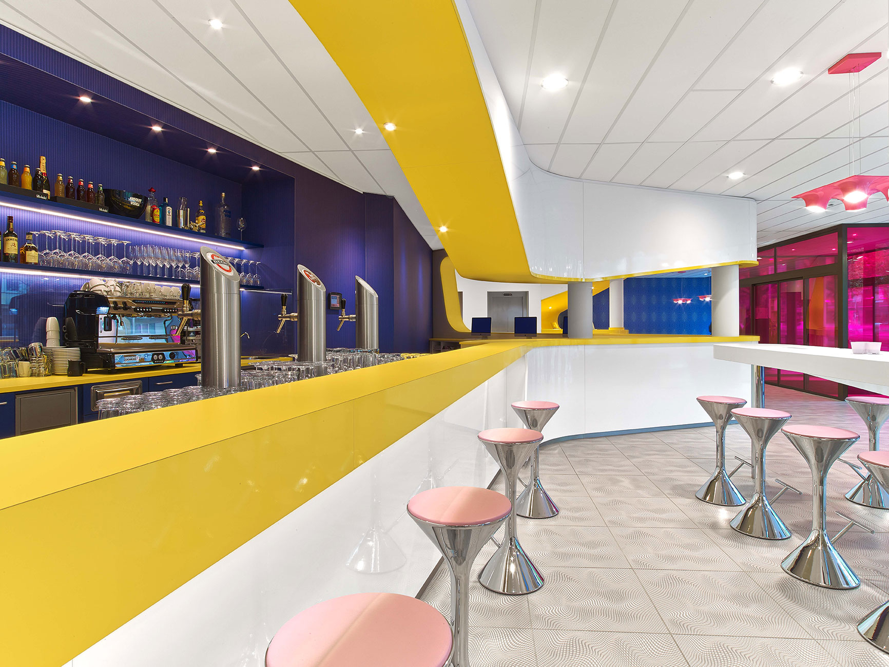 Moderne Bar des Designhotels in Hannover mit gelbem Bartresen und pinken Hockern