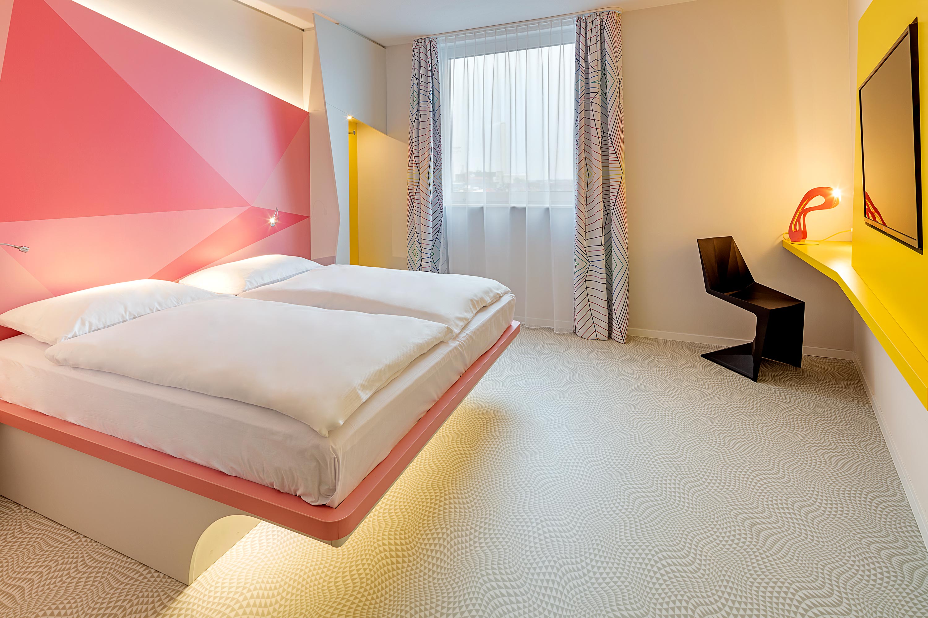 Ein rosa Bett in einem gelben Hotelzimmer
