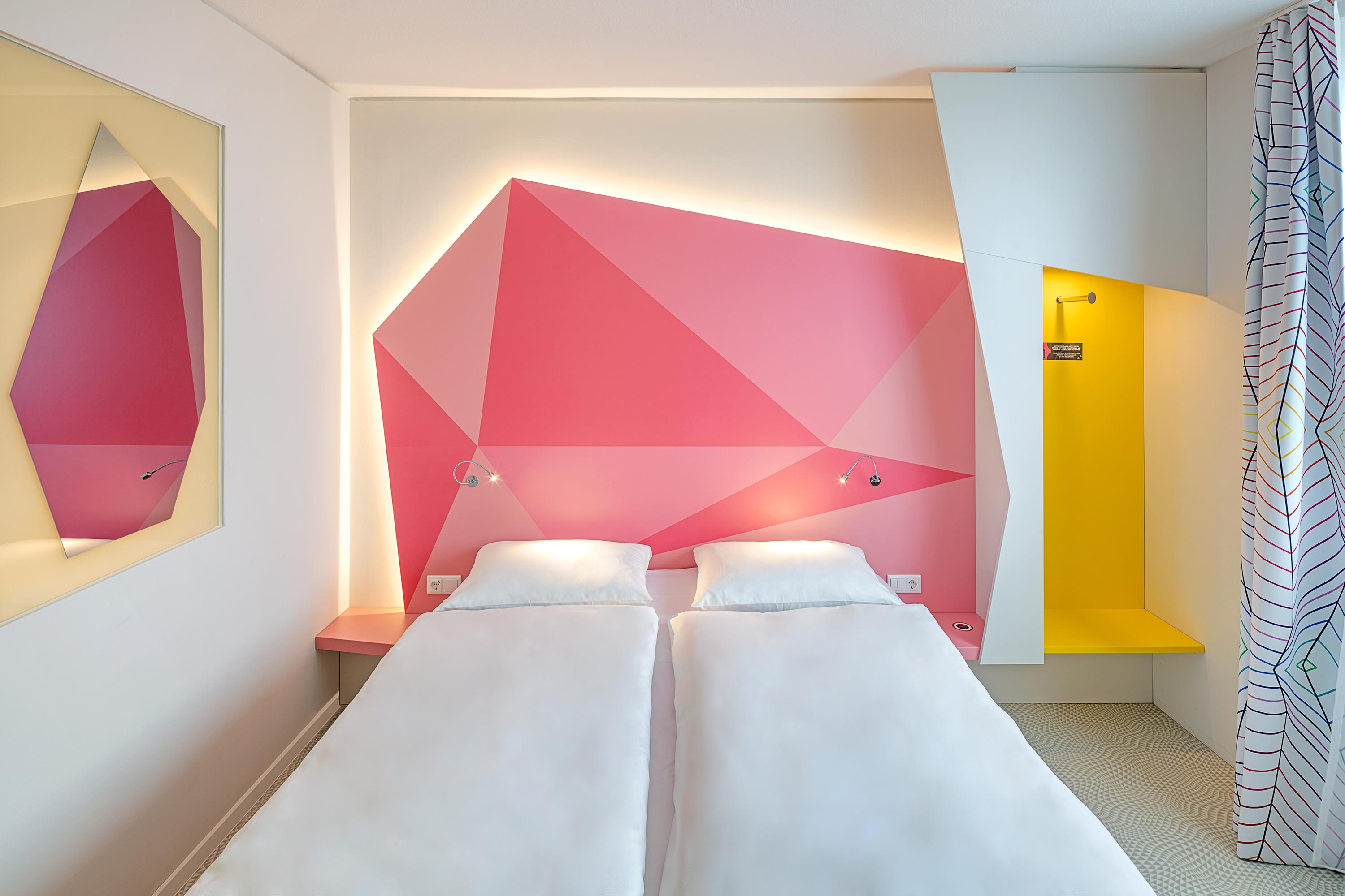 Ein Bett vor einer rosa beleuchteten Wand 