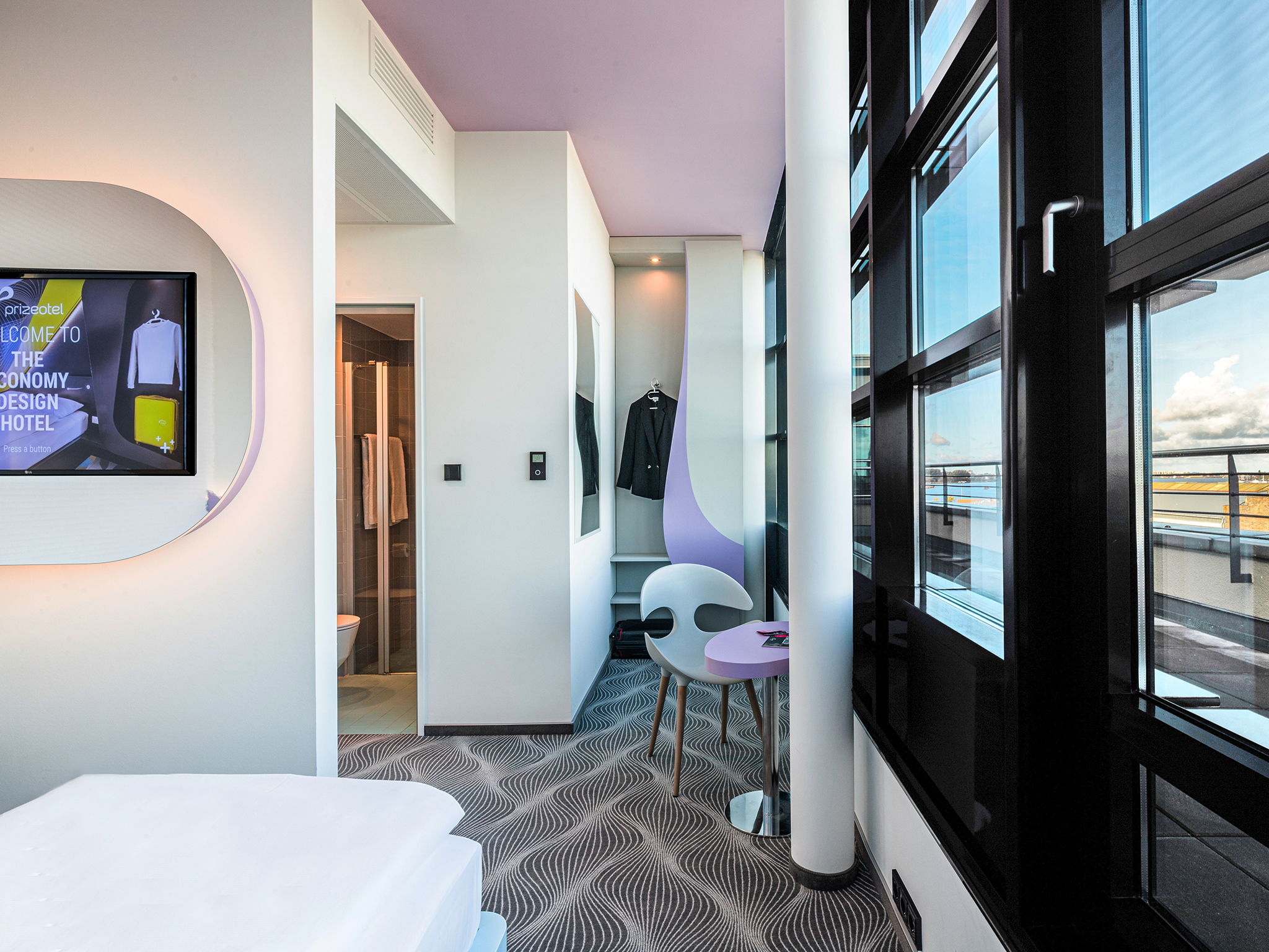 Hotelzimmer des prizeotel Rostock-City mit Badezimmer und offenem Kleiderschrank
