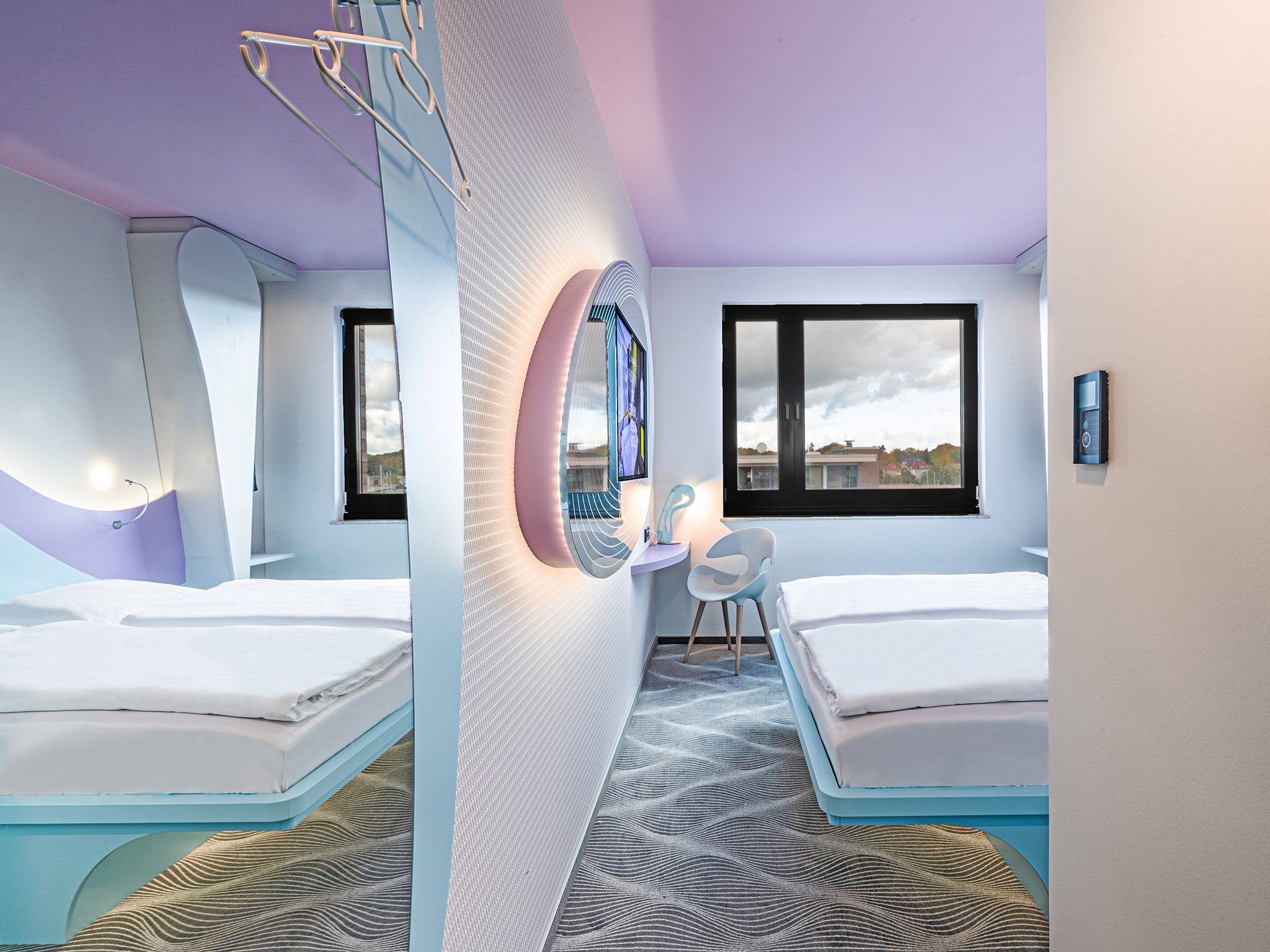A bright two-room suite of the prizeotel in Rostock with a view of the beds