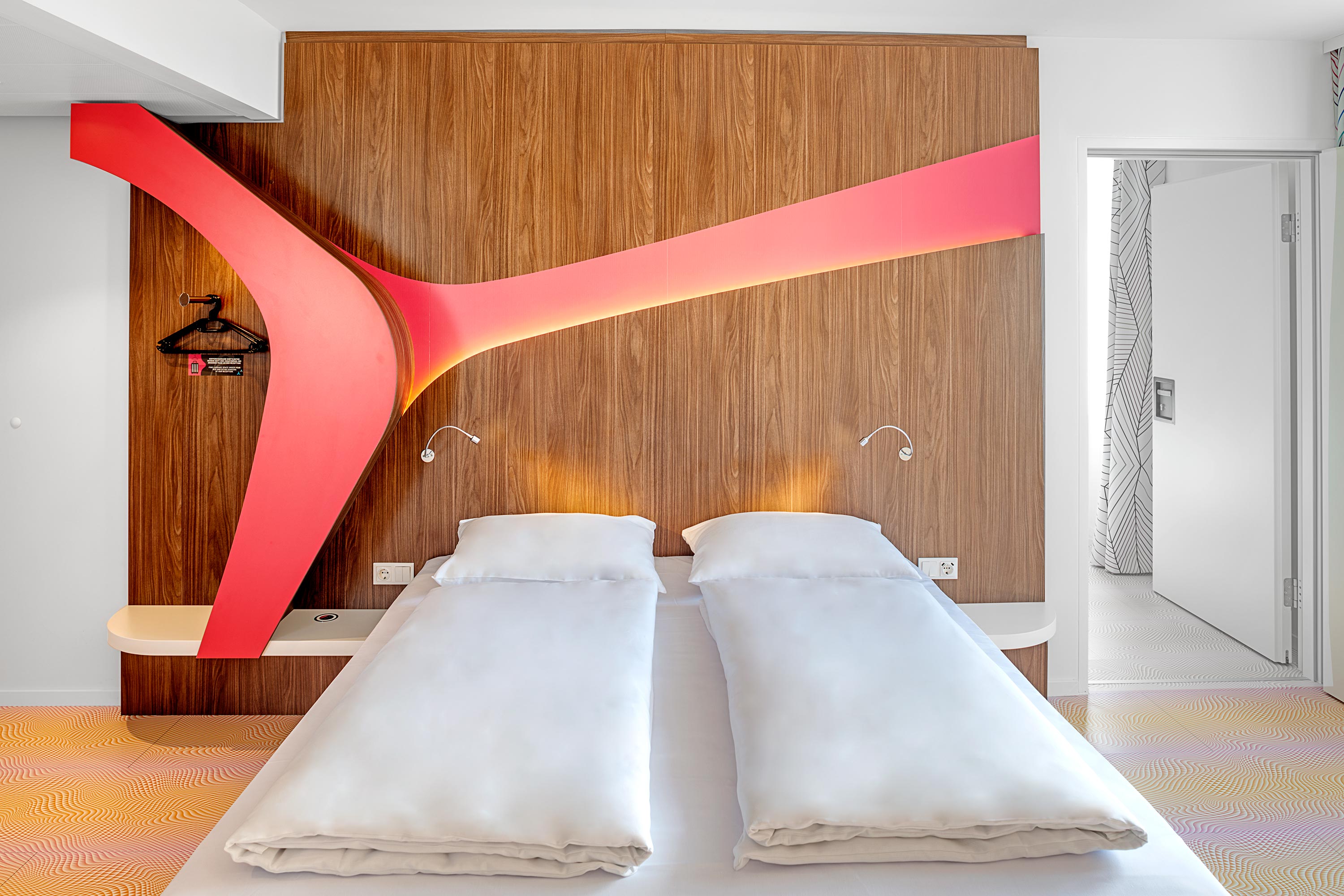 Ein Doppelbett mit einer roten Holzwand dahinter