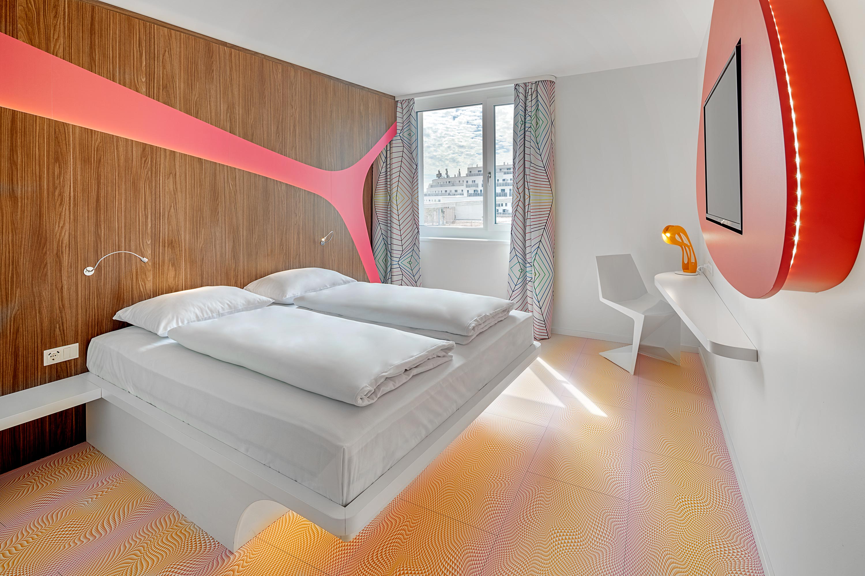 Ein Doppelbett in einem Hotelzimmer in Münster mit schönen Vorhängen und einem roten Spiegel