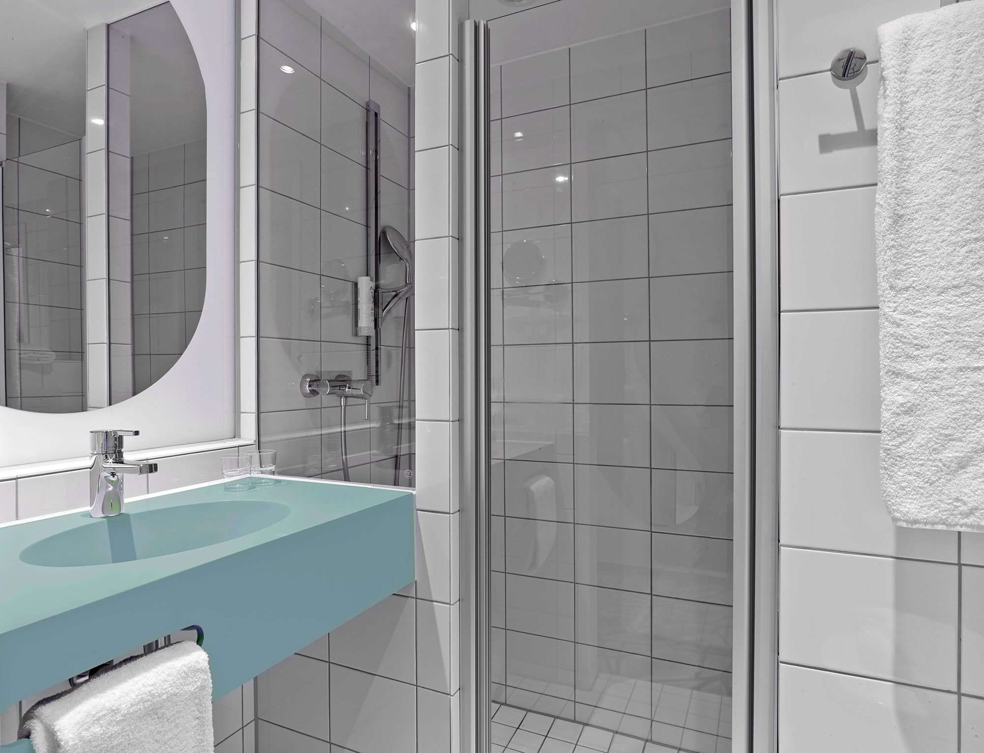 Badezimmer eines Hotelzimmers mit Duschkabine und blauem Waschbecken