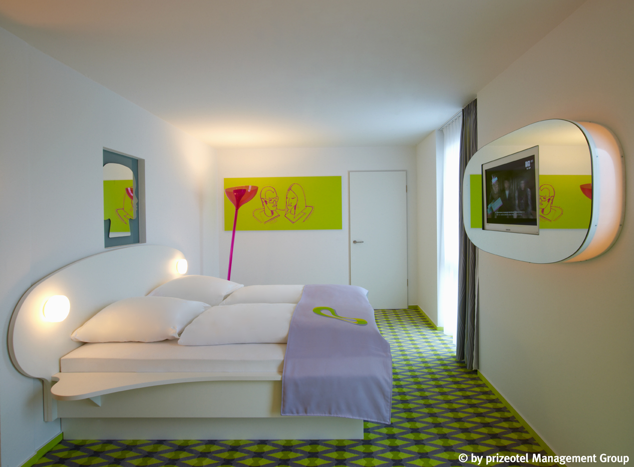 Grün gestaltetes Doppelzimmer mit pinker Stehlampe und Kunst